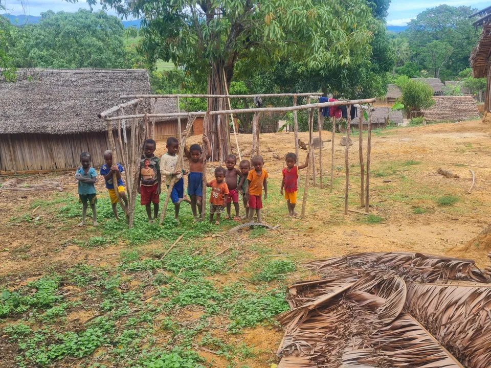 Einheimische Kinder in Madagaskar spielen gemeinsam im Freien in einem traditionellen Dorf mit strohgedeckten Häusern
