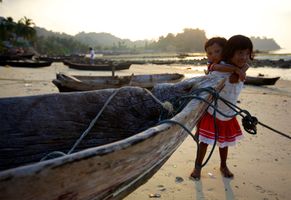 Mokenkinder neben einem Einbaum, ein verbreiteter Bootstyp bei indigenen Völkern
