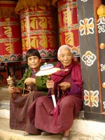 Bhutaner vor Gebetsmühlen sitzend